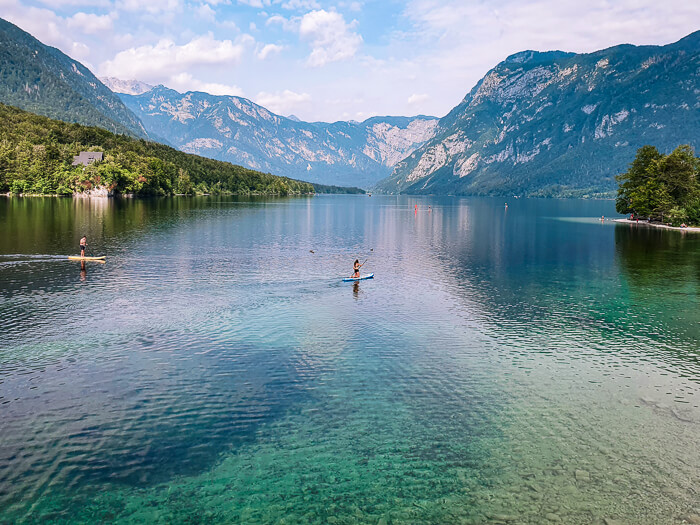 A paddle boarder on the crystal clear Lake Bohinj surrounded by Julian Alps, one of the best places to include in your 5-day Slovenia itinerary.