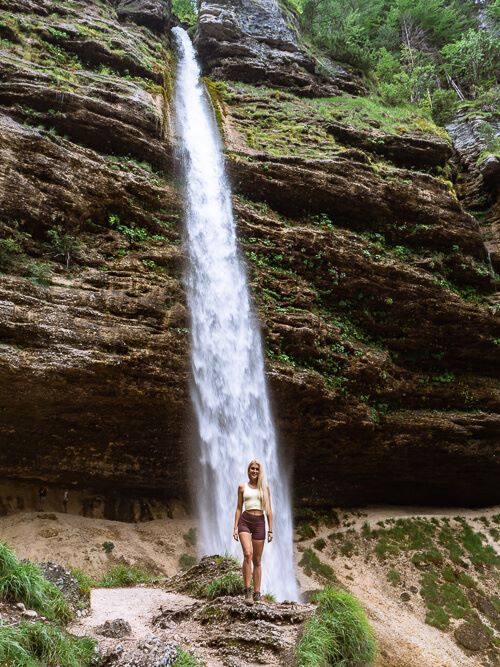 A woman posing in front of the impressive Slap Peričnik Waterfall in Triglav National Park, Slovenia
