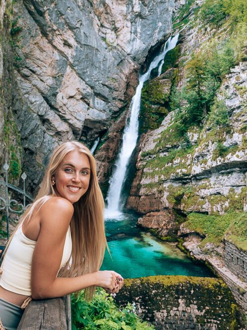 A woman posing with the mesmerizing Savica Waterfall near Lake Bohinj, Slovenia