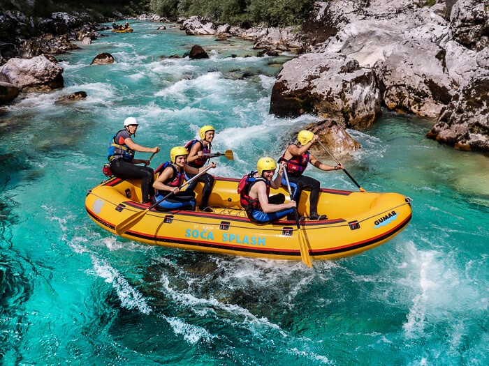 A group of people sitting in a boat rafting on the Soca River, one of the best things to do in Slovenia