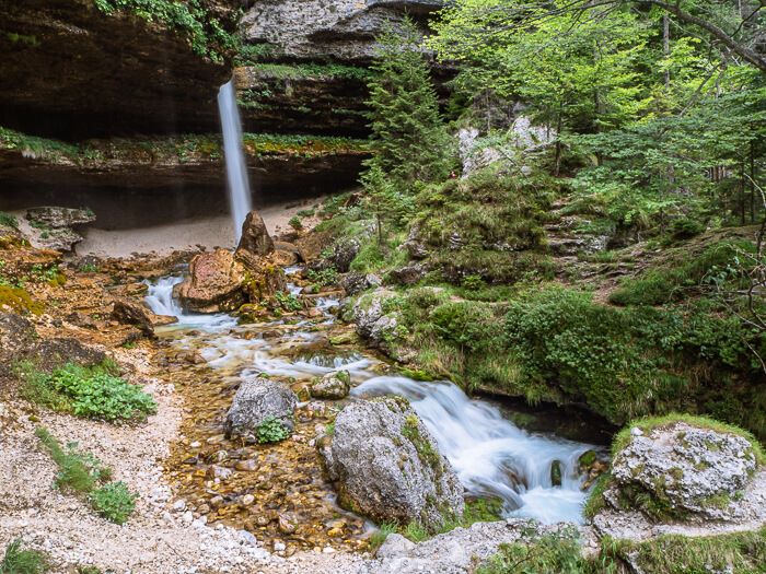 the small upper Peričnik waterfall surrounded by green vegetation and limestone rocks 