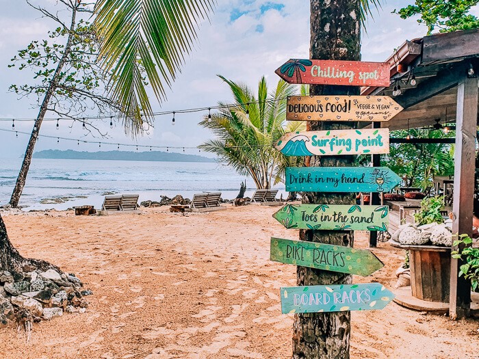 A beach club with sunbeds and colorful signs at Paunch Beach, one of the best surf spots in Bocas del Toro, Panama