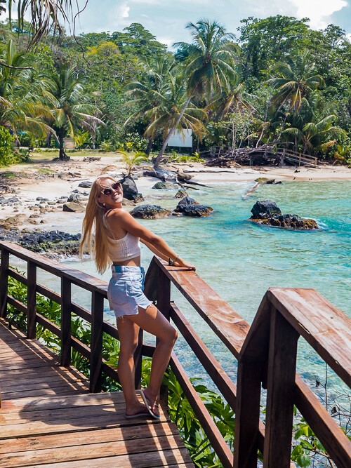 a woman standing on a boardwalk overlooking the Red Frog Beach at Isla Bastimentos