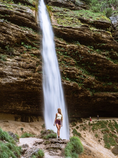 A woman standing in front of Pericnik Waterfall in Slovenia