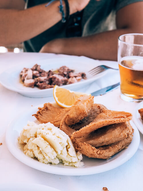 two white plates with Greek seafood dishes