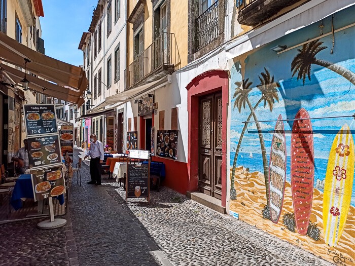 A narrow historical street lined with restaurants in Funchal Old Town.