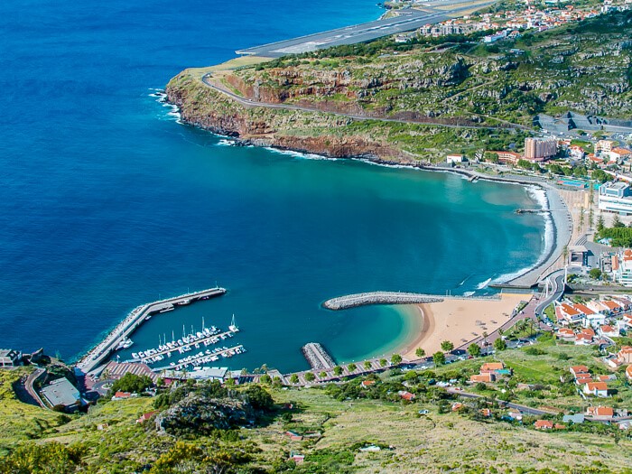 An aerial view of the crescent-shaped Machico Bay Beach with its golden sand, one of the few sandy beaches near Funchal