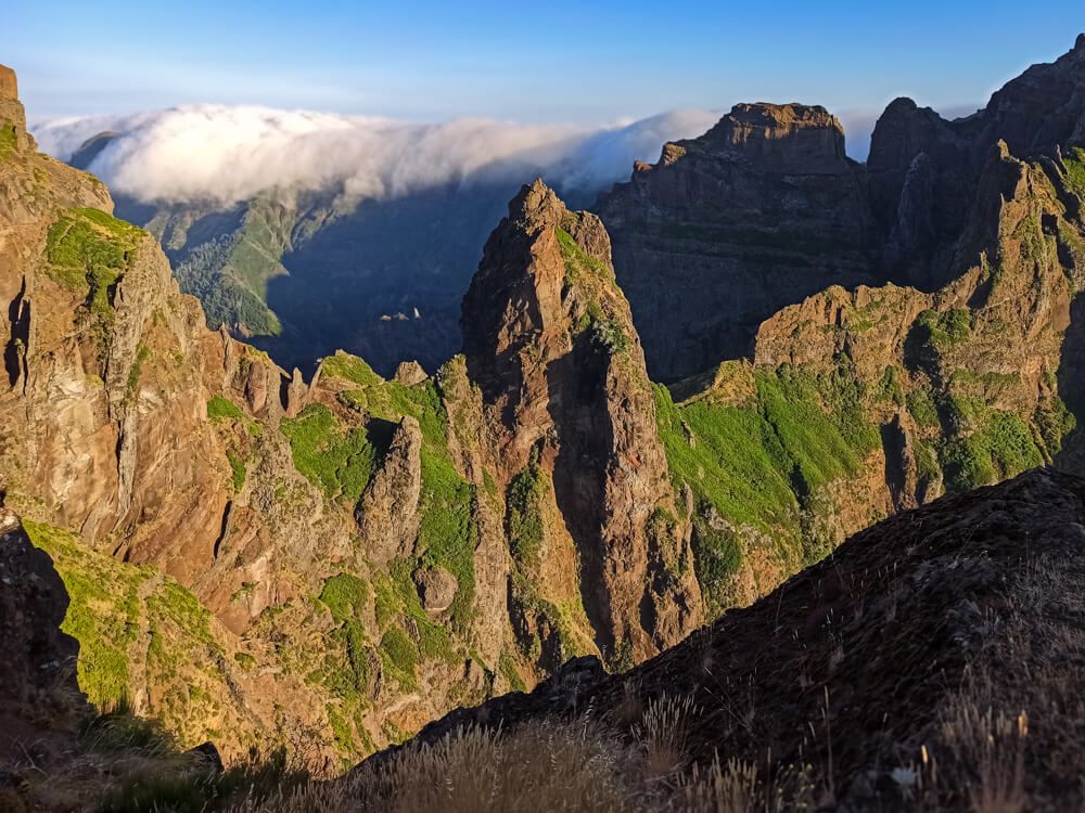 A steep mountain ridge with sharp rocky peaks and green vegetation on its slopes in central Madeira.