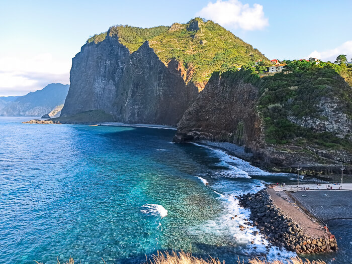 Turquoise ocean and vertical coastal cliffs viewed from Miradouro do Guindaste viewpoint next to Faial Beach in Madeira.