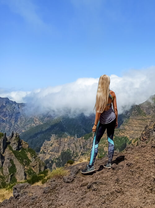 a woman admiring the views along the Pico do Arieiro to Pico Ruivo trail, one of the best hikes in Madeira
