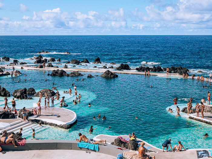A large outdoor pool full of people at Porto Moniz Natural Swimming Pools, a great alternative to beaches in Madeira