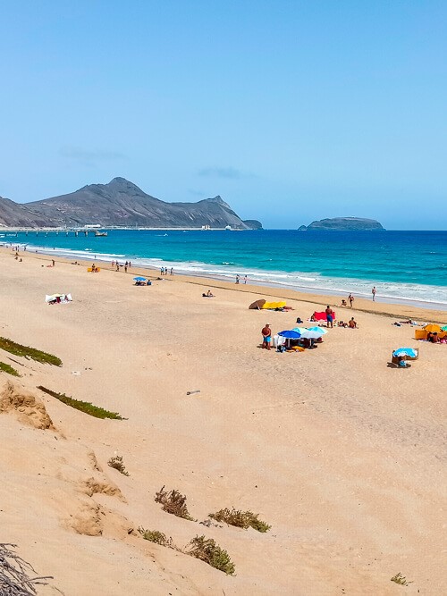 Beach goers with colorful umbrellas on the long sandy beach of Porto Santo.