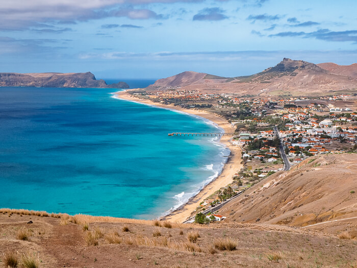 A panoramic view of Porto Santo Beach with its long stretch of yellow sands and turquoise water.