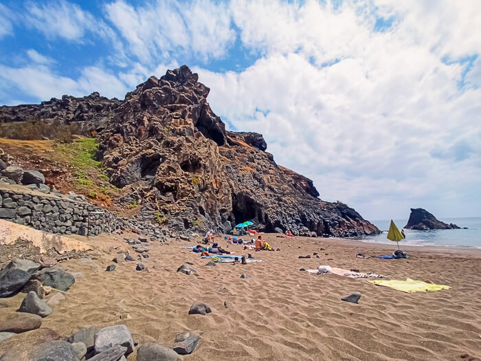 Volcanic cliffs and brown sand of Prainha Beach, one of the best sandy beaches in Madeira
