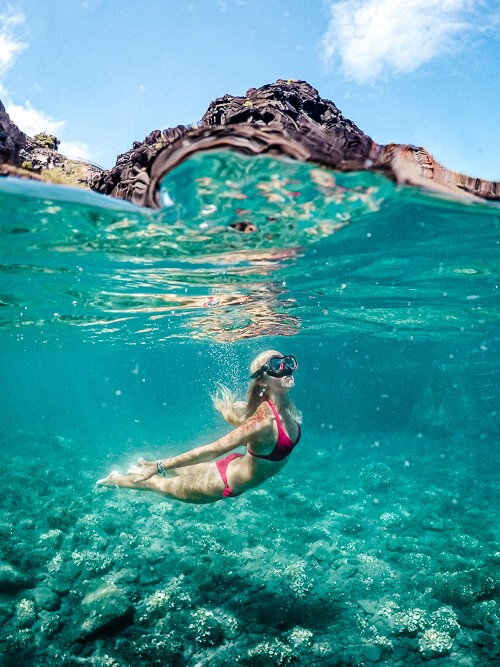 an underwater photo of a woman swimming in the clear water of Seixal Natural Pools of Madeira