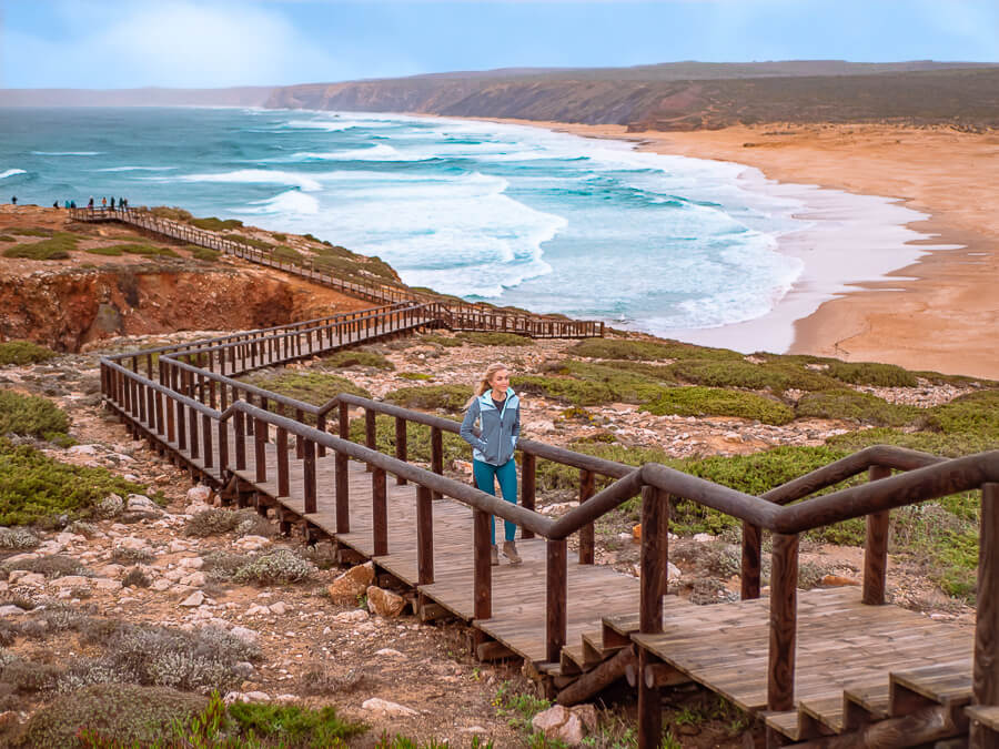 Me walking on a boardwalk overlooking the huge Praia da Bordeira, a popular beach among surfers