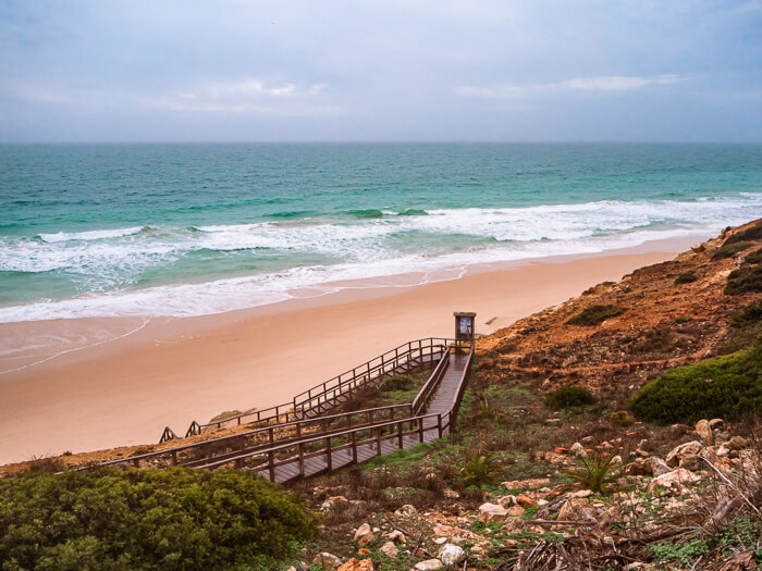 A long sandy beach and strong waves at Salema on the Rota Vicentina walking trail, one of the best Algarve hikes