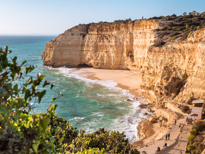 a sandy cove surrounded by tall limestone cliffs at Praia do Vale de Centeanes on the Seven Hanging Valleys hike in the Algarve, Portugal