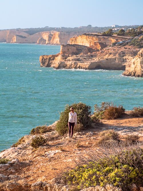 A woman standing on a rocky headland on the coast of the Algarve