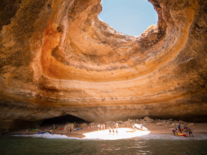 People standing on a small beach inside Benagil Cave, one of the most famous attractions in Algarve.