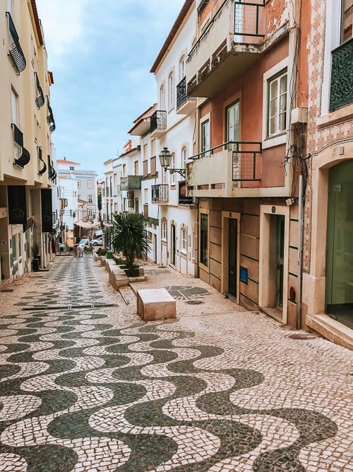 A cobblestone street lined with pastel colored buildings in Lagos, Algarve