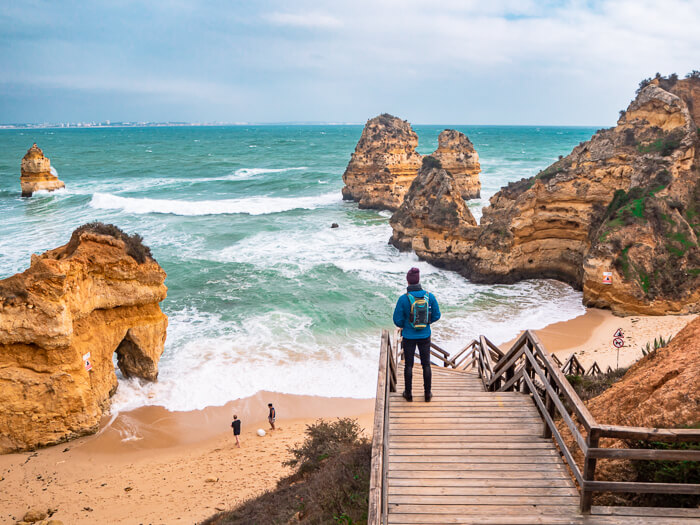 My boyfriend standing on a wooden staircase at Praia do Camilo, one of the best beaches in the Algarve.