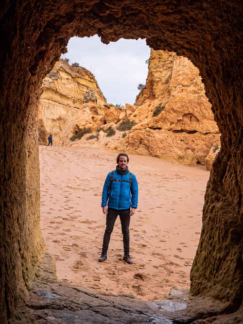 My boyfriend standing in front of a tunnel carved into limestone cliff at Praia dos Estudantes.
