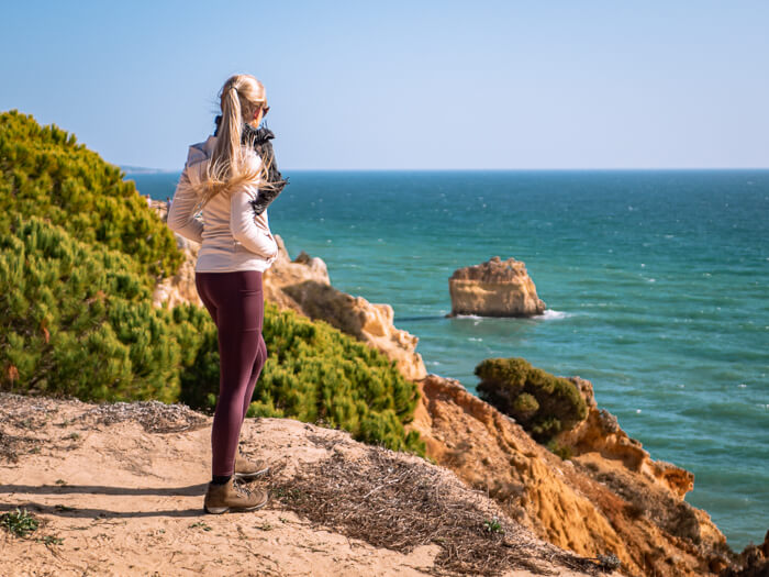 A woman enjoying the view over the golden cliffs and turquoise sea in Algarve