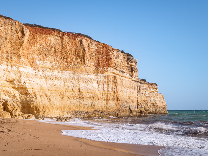 golden sand and tall cliffs rising from the emerald sea at Benagil Beach in southern Portugal