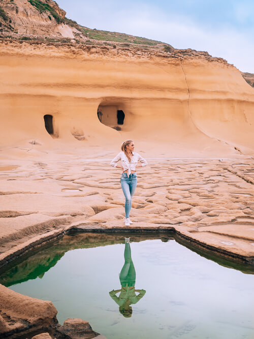 Me posing next to a saltwater pond at the Xwejni Salt Pans, one of the top things to do in Gozo