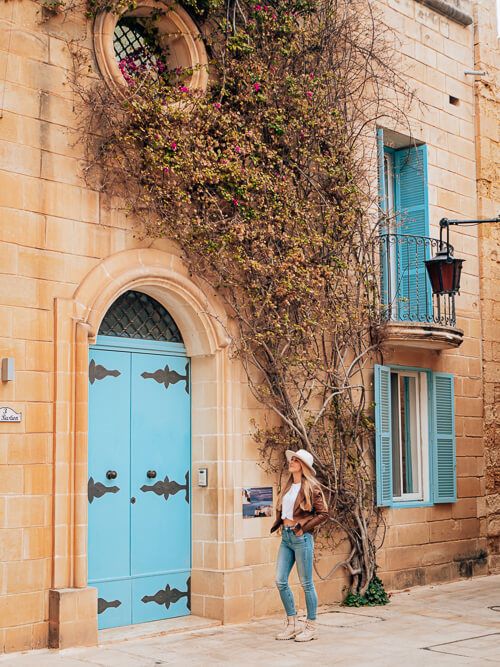 Me posing in front of a wooden blue door, a popular Instagram spot in Mdina