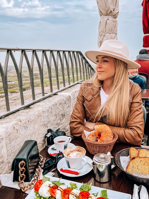 A woman sitting at a table at Fontanella Tea Garden, an Instagrammable restaurant in Mdina, Malta