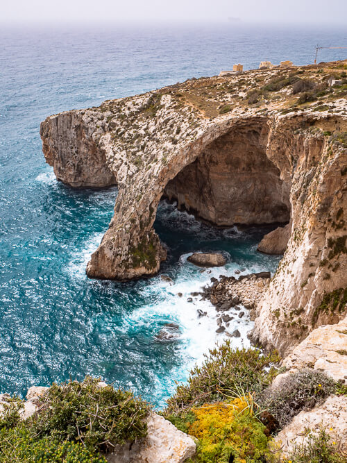 A huge rock arch rising out of the sea at Blue Grotto, one of the most famous Malta Instagram spots