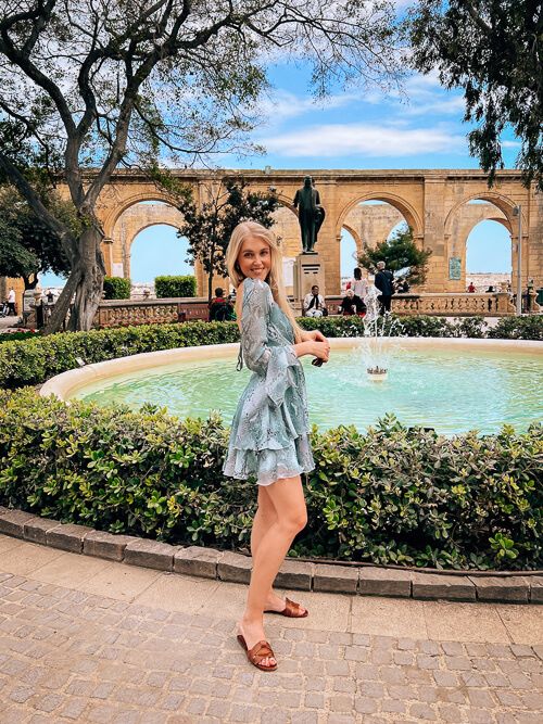 a woman standing in front of a fountain at Upper Barrakka Gardens, a popular public park in Valletta