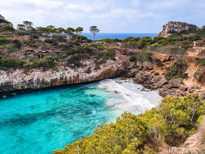 The small cove of Calo des Moro with vivid blue water surrounded by cliffs, a great day trip destination from Cala d'Or