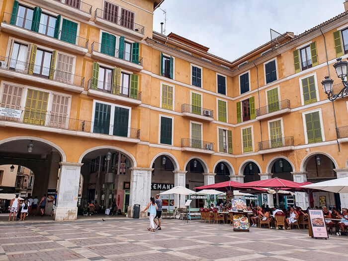 Historical yellow buildings surrounding Placa Major, the main square of Palma de Mallorca.