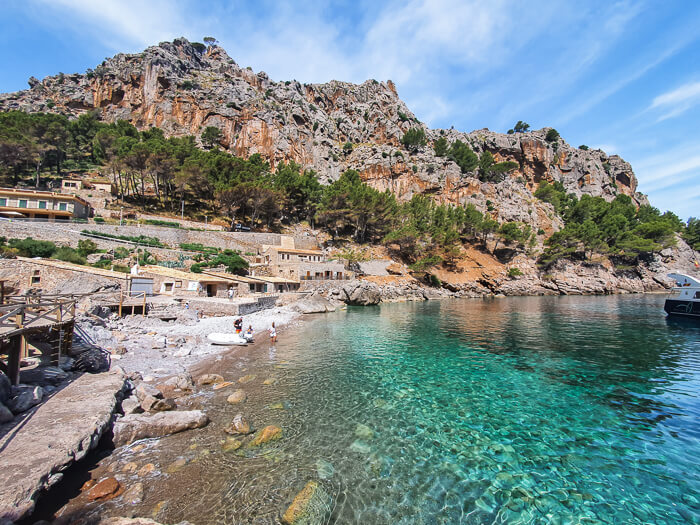 A small pebbly cove with clear turquoise water surrounded by mountains at Sa Calobra beach