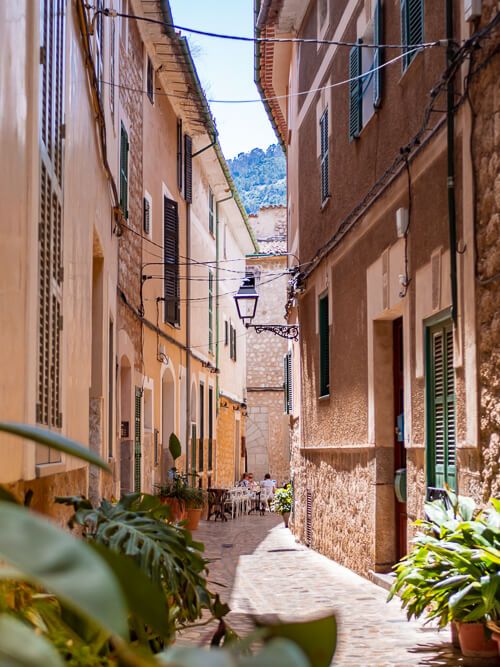 A narrow cobbled street lined with beige stone houses in the historic center of Soller.
