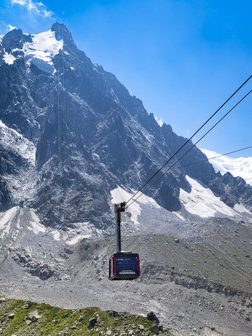 A cable car heading up a steep slope to Aiguille du Midi peak next to Mont Blanc