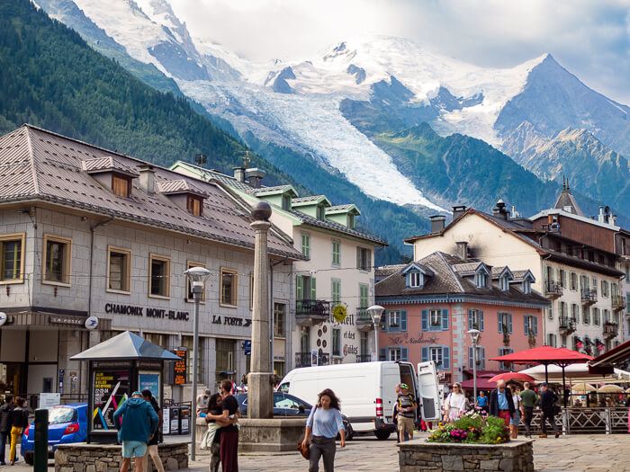 The bustling square of Place Balmat in Chamonix town center, surrounded by historical buildings and mountain views.