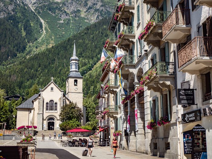 A church and an apartment building with flower-adorned balconies in the center of Chamonix, France