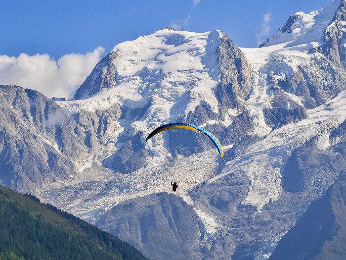 A paraglider flying over the Chamonix valley with views over glaciers and the Mont Blanc massif.