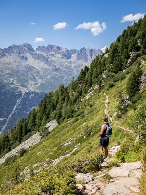 My boyfriend hiking through a green meadow along Grand Balcon Nord, one of the best day hikes in Chamonix