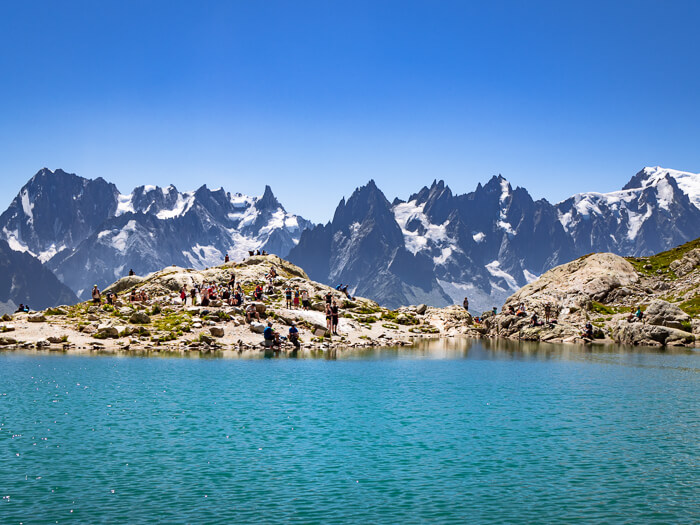 blue-green water and a rocky shore at the Lac Blanc lake overlooking the peaks of the Mont Blanc Massif