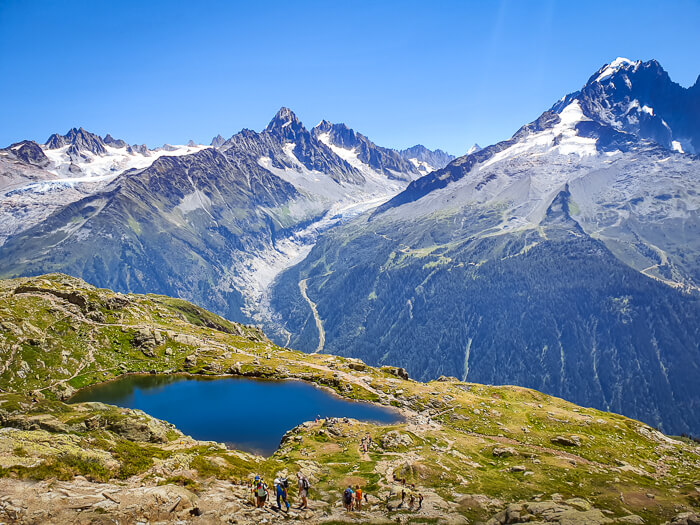 Small blue Lac de Cheserys lake surrounded by alpine grasslands and dramatic mountain scenery