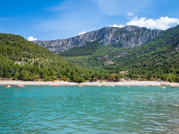 The Lake of Sainte-Croix with clear turquoise water and a backdrop of forest-covered hills 