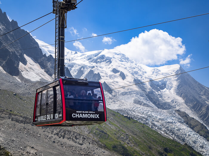 Cable car transporting passengers up to Aiguille du Midi peak next to the snow-capped Mont Blanc