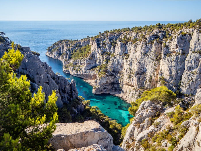 A view over the neon blue water and towering cliffs of Calanque d'En Vau, one of the most beautiful places in this Provence road trip itinerary
