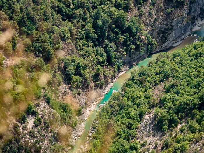 Winding blue-green Verdon River surrounded by rugged cliffs and trees, viewed from a belvedere at Route des Cretes Gorges du Verdon