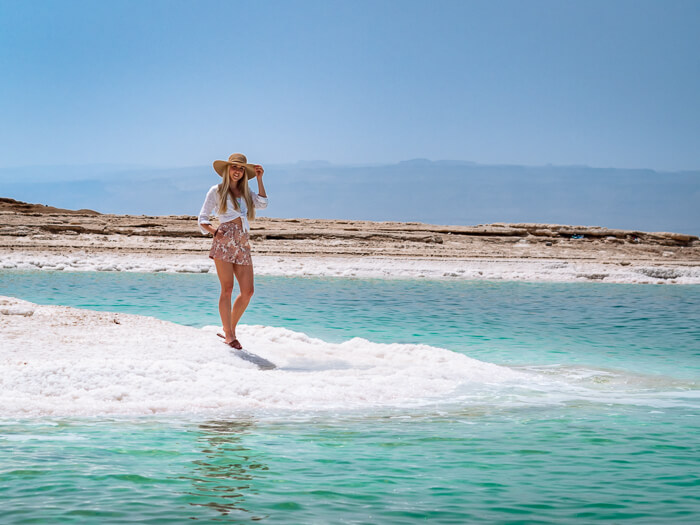 A woman standing on a beach covered in salt crystals at Dead Sea, one of the best places to visit on this 10-day Jordan itinerary